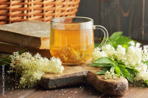Meadowsweet floral herbal tea in glass cup with flowers nearby on the wooden rustic table, antiviral homemade drink, closeup, copy space, natural medicine and healthy herbal tea concep