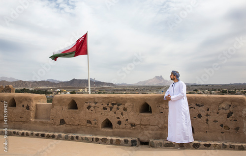 omani man in traditional outfit looking at the landscape of countruside