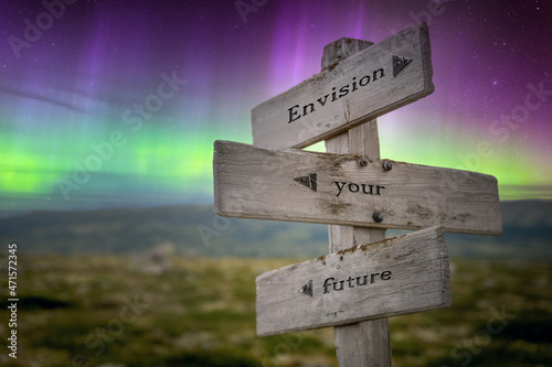 envision your future text quote on wooden signpost outdoors in nature with northern lights above.
