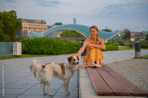 in Rike park a girl sits on a bench with a dog in tbilisi