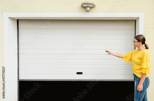 Garage door PVC. Girl or young woman holds remote controller for closing and opening garage door 