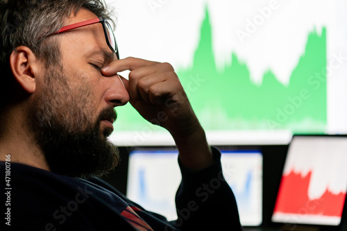 Depressed businessman in front of computer with graph of unsuccessful business on the screen. High quality photo.