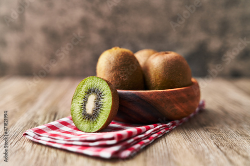  Bowl of bunch of kiwis and slice on a wooden table