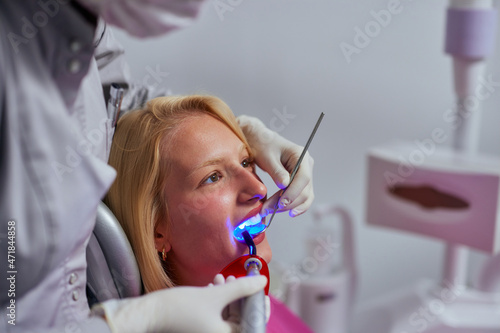 Dentist using ultraviolet light on the patient's teeth