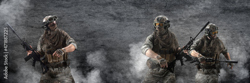 Three mercenary soldiers during a special operation in the smoke against the background of a dark concrete wall - photo with copy space in center. Format photo 3x1.
