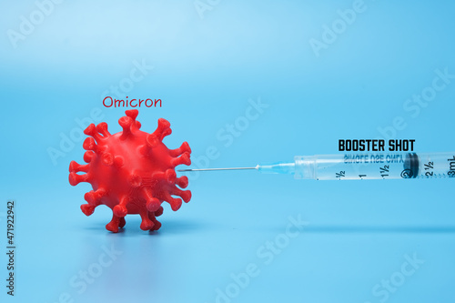 A picture of 3D printed coronavirus with omicron variant word, vaccine and booster shot word. Booster shot helps to fight new variant.