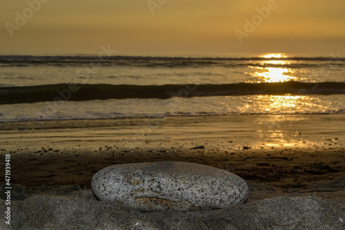 Rock on the shore of the beach at sunset.
