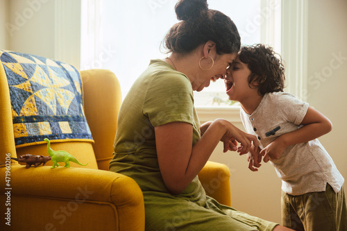 Young mother and son imitating a dinosaur at home