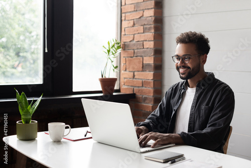 Young man student using laptop computer at home, studying online. Creative professional working in office. Distance study, work from home, e-learning, business, meeting online