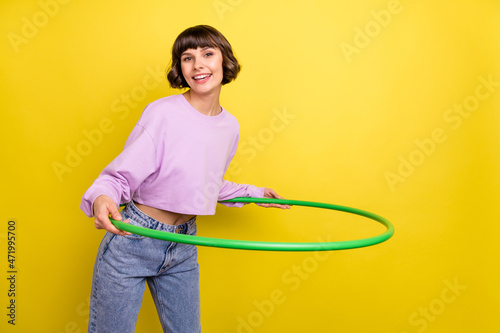 Portrait of attractive cheerful girl doing exercise with ring copy space isolated over bright yellow color background