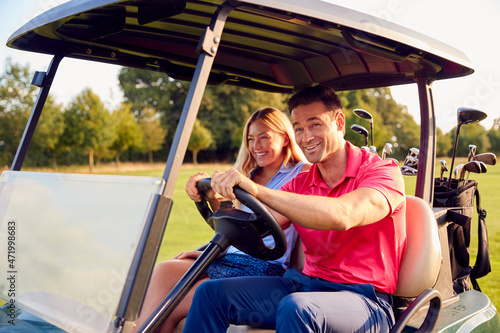 Couple Driving Buggy Playing Round On Golf Together