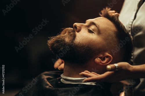 Close shot of a young man beard while he is sitting at a barbershop