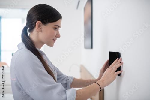 Focused calm dark-haired lady mounting a gadget