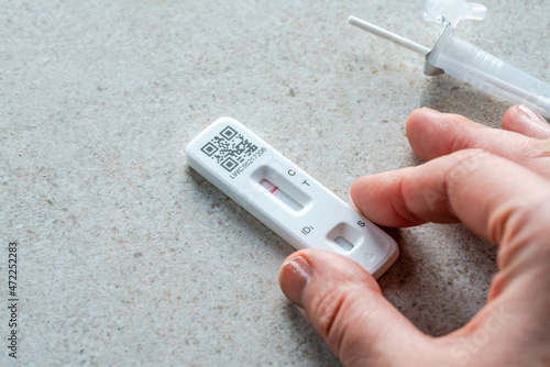 Female hand holds rapid lateral flow test device which shows negative Covid19 result.