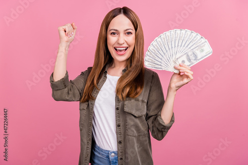 Photo of mature excited woman celebrate success winner money cash dollars isolated over pink color background