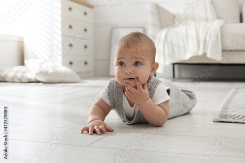 Cute baby crawling on floor at home