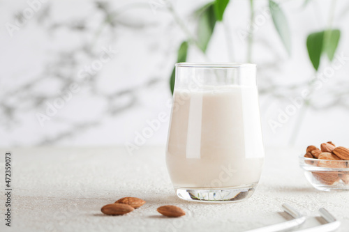 Vegan almond milk in glass with nuts on white background. Copy space. Healthy vegetarian food. selective focus. Non dairy alternative milk