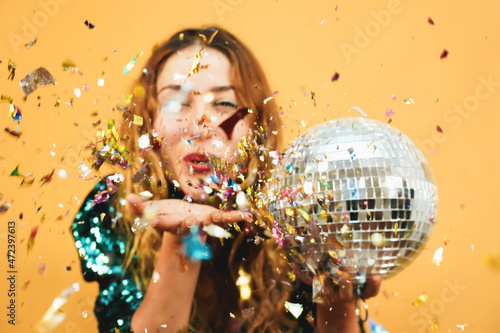 Blurred happy girl blowing confetti holding vintage disco ball - Defocused photo