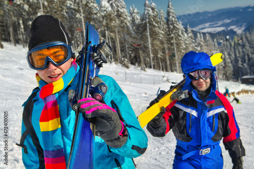 Skiers holding skies; blue jacket; horizontal orientation