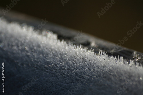 Cristalli di neve e ghiaccio sulla balaustra in legno di un sentiero, in una mattinata fredda e invernale