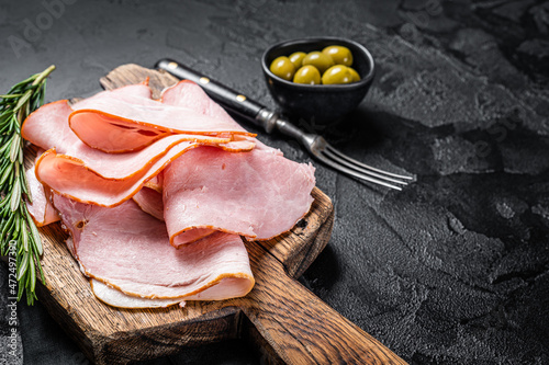 Pork ham slices on cutting board, Italian Prosciutto cotto. Black background. Top view. Copy space