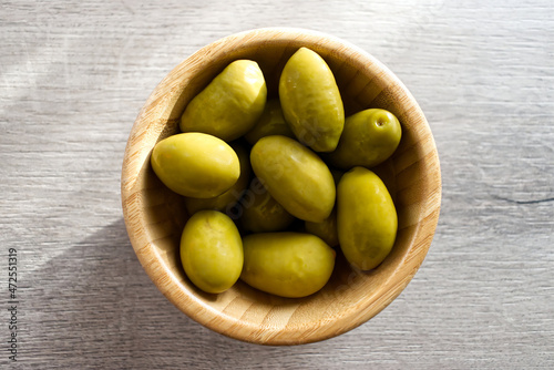 Bowl with Italian green olives from Cerignola. Bella di Cerignola Italian olives on wooden table. Top view
