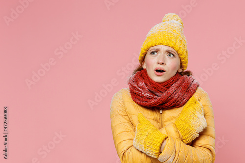 Shocked shocked amazed young woman 20s years old wears yellow jacket hat mittens look aside keep mouth open hold hands crossed frowning isolated on plain pastel light pink background studio portrait.