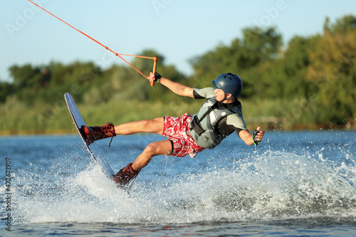 Teenage boy wakeboarding on river. Extreme water sport