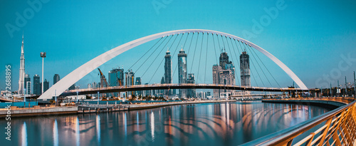 colorful sunset over Dubai Downtown skyscrapers and the newly built Tolerance bridge as viewed from the Dubai water canal