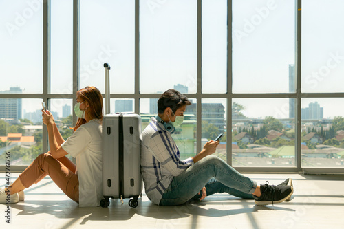 Asian couple of tourists in waiting area of airport terminal sit and nap before departure and check-in.