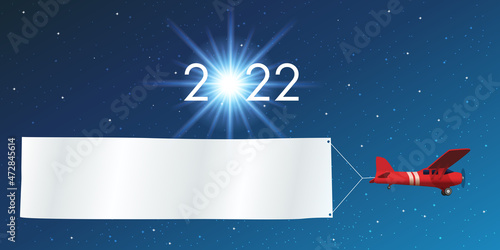 Carte de vœux 2022 montrant un avion rouge tirant une banderole blanche pour souhaiter la bonne année, devant un ciel étoilé.