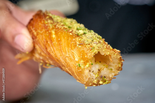 Arabian Traditional Desserts rolls - Cream and cheeses with pistachio flavor and nuts topping on gray background