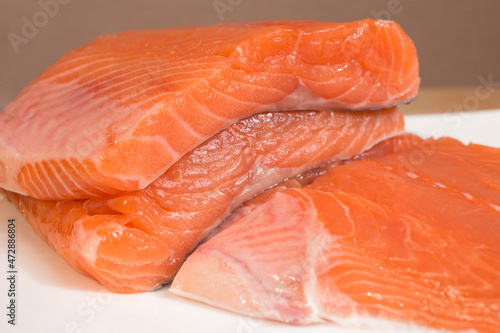 Close-up of fresh-cut salmon loins piled on a flat plate with creative blur. Healthy food ingredients. Nutrition and fish.