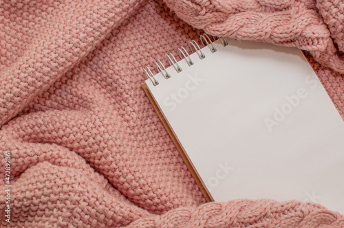 a spring-loaded notebook on a pink knitted plaid