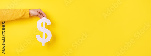 dollar symbol in hand over yellow background, panoramic layout