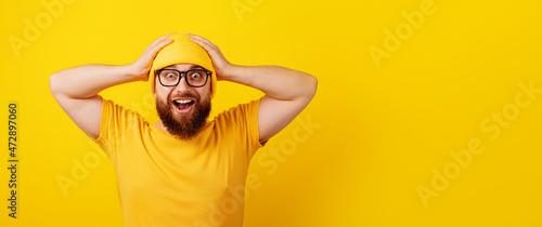 surprised man in glasses over yellow background, wow emotion, concept of promotions or big discounts, panoramic layout