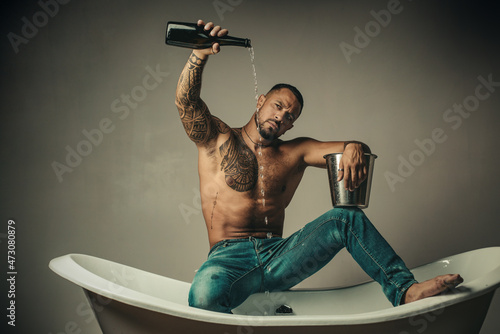 Sexy undress man sit on bathtub in bathroom, men holiday with champagne. Celebrating christmas or birthday. Private sex party.