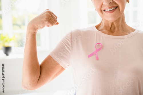 Mature senior elderly strong woman in pink t-shirt with pink ribbon supporting fighting for breast cancer movement. Togetherness, oncology recovery concept