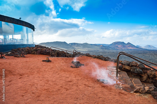 Steam arising from volcano used for cooking in Timanfaya National Park on Lanzarote, Canary Islands, Spain. Volcanic landscape covered with red lava stones and ash