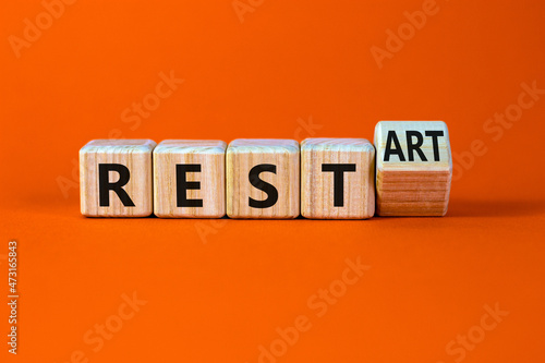 Rest and restart symbol. Turned a wooden cube and changed the word rest to restart. Beautiful orange table, orange background, copy space. Business, rest and restart concept.