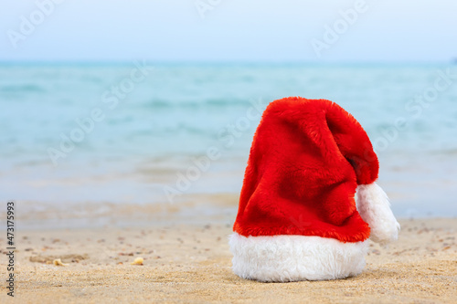 Santa hat on sandy beach. Concept of celebrating christmas