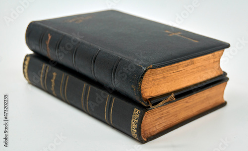 Two antique hymnals in a stack from 1910 and 1914. The edges are finished with real gold. Isolated on a white background.