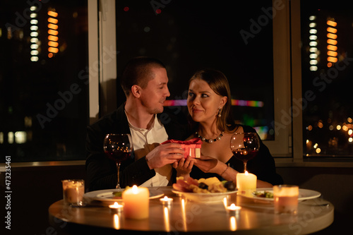 Real candlelight dinner for two, valentine's day date, couple having dinner man giving a woman a gift, romantic family relationship