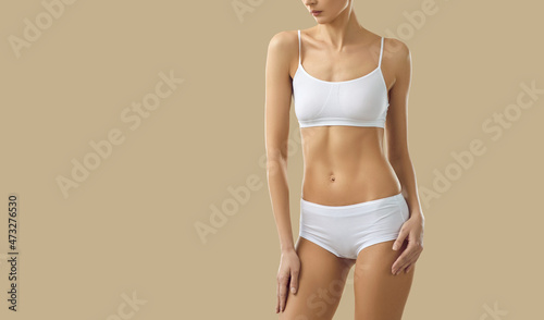 Close up of toned slim female model in underwear isolated on yellow studio background. Sporty thin woman in intimate underclothing garment recommend sport clothes collection. Diet, copy space.