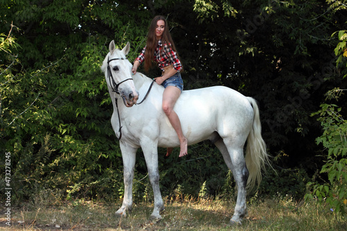 Beautiful cowgirl bareback ride her horse in woods glade at sunset