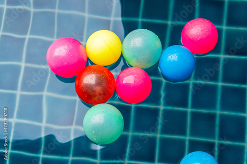 Many colorful little balls are floating in the pool in daytime, holiday or vacation time , pool party toys.