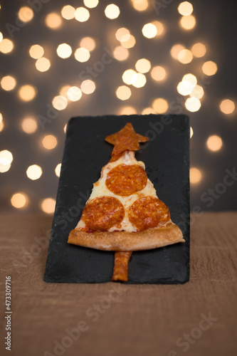 A slice of pepperoni pizza that resembles a Christmas tree. Christmas pizza. New Year