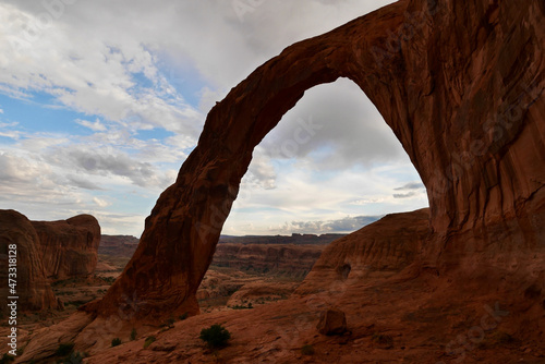 Panorama view of Corona Arch near Moab at sunset after thunderstorm. Typical Utah red rock formations.