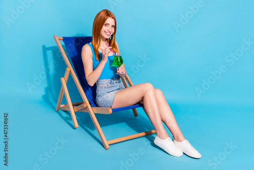 Photo of adorable sweet young lady dressed bodysuit top smiling having rest chaise longue isolated blue color background