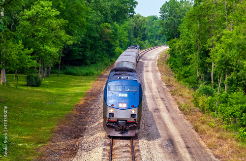 Amtrak passenger train traveling from Chicago, Illinois to Detroit, Michigan through verdant Michigan countryside